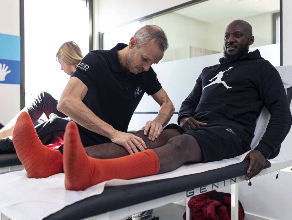 kiné pour sportif Lyon - Ludovic contrôle les articulations du genoux d'un basketeur professionnel