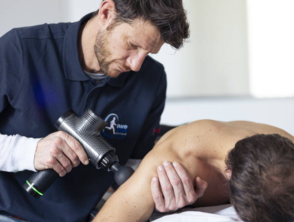 RDV ostéopathie Lyon. Julien utilise un pistolet de massage sur le triceps de son patient.